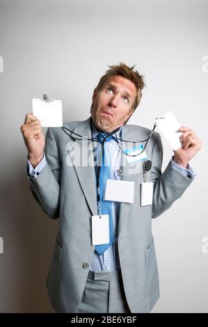 Verwirrt Geschäftsmann trägt eine Sammlung von leeren Namensschildern Blick auf leere Kopie Raum mit einem lustigen Ausdruck Stockfoto