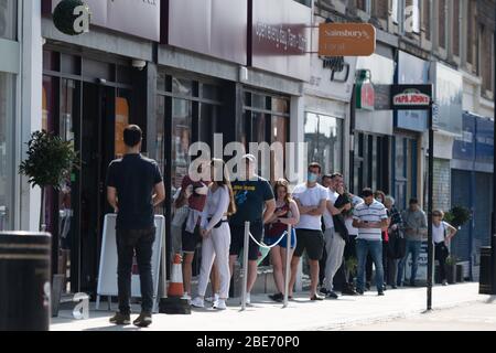 Am Ostersonntag Schlange stehen vor Sainsbury’s Supermarkt, beobachten soziale Distanzierung unter Lockdown. Stockfoto