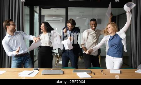 Überglücklich multiethnische Kollegen haben Spaß beim Feiern im Büro Stockfoto