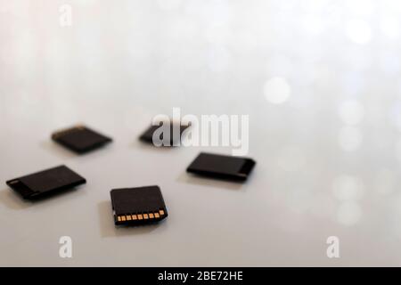 Schwarze Speicherkarten in kreisförmiger Form auf einem weißen Tisch platziert. Foto mit Bokeh und Kopierraum. Stockfoto