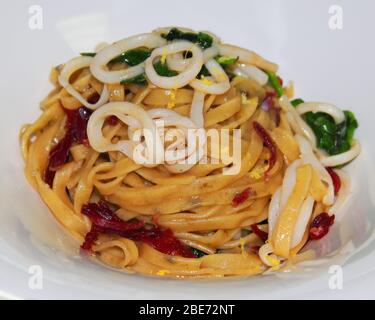 Italienisches Nudelgericht mit Rinderspeck und Tintenfischringen Stockfoto