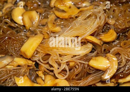 Gekochte Spaghetti in Pilzsoße mit Pilzstücken. Nahaufnahme Stockfoto