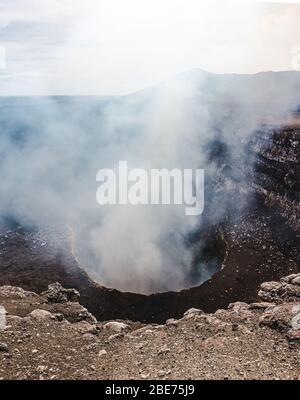 Blick hinunter in den dampfenden Krater des Volcan Masaya, einem aktiven Vulkan, der mit geschmolzener Lava in der Nähe von Granada, Nicaragua, gefüllt ist Stockfoto