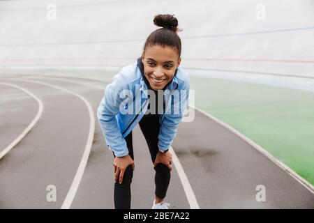 Attraktive junge afrikanische Sportlerin, die sich nach dem Rennen im Stadion ausruht Stockfoto