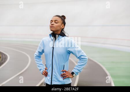 Attraktive junge afrikanische Sportlerin, die nach dem Rennen im Stadion ausruht, Augen geschlossen Stockfoto