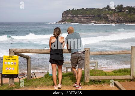 Sydney, Australien. Montag, 13. April 2020. Avalon Beach in Sydney war für das lange Osterwochenende geöffnet, aber am Ostermontag schlossen Beamte den Strand, dann errichteten Beamte Strandverschlossene Schilder wegen COVID-19. Egal, die Leute gingen weiter zum Sport oder Surfen in den Strand, während andere (im Bild) die Schließung beobachteten. Credit Martin Berry/Alamy Live News Stockfoto