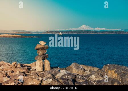 Inukshuk und Mt Baker weit weg. Foto aufgenommen vom beliebten Yachthafen Oak Bay in Victoria Stockfoto