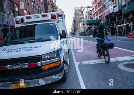 New York City, Usa. April 2020. Ein Mann fährt während der Coronavirus-Krise in NYC an einem Krankenwagen vorbei die Vereinigten Staaten sind heute das Land mit den am meisten bestätigten Coronavirus-Todesfällen der Welt. Allerdings haben Staaten wie New York, das Epizentrum der Infektionen im Land, begonnen, die Kurve abzuflachen. Quelle: SOPA Images Limited/Alamy Live News Stockfoto
