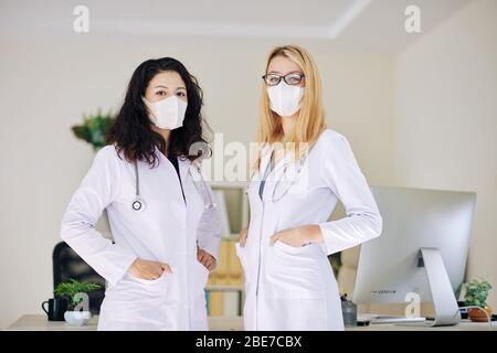 Porträt von zwei jungen selbstbewussten Medizinpraktikanten in Schutzmasken, die im Krankenhaus arbeiten Stockfoto