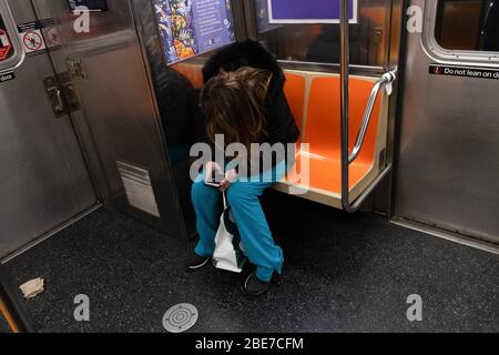 New York City, USA. April 2020. Während der Coronavirus-Krise benutzt eine medizinische Mitarbeiterin ihr Mobiltelefon, während sie in der NYC-U-Bahn fährt.die Vereinigten Staaten sind heute das Land mit den am meisten bestätigten Coronavirus-Todesfällen der Welt. Allerdings haben Staaten wie New York, das Epizentrum der Infektionen im Land, begonnen, die Kurve abzuflachen. Quelle: Braulio Jatar/SOPA Images/ZUMA Wire/Alamy Live News Stockfoto