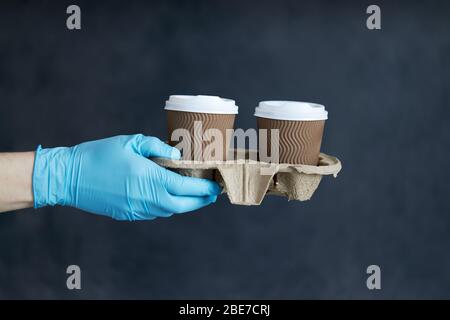 Kurier in Schutzmaske und medizinischen Handschuhen liefert Essen und Kaffee zum Mitnehmen. Lieferservice unter Quarantäne, Krankheitsausbruch, Coronavirus covi Stockfoto