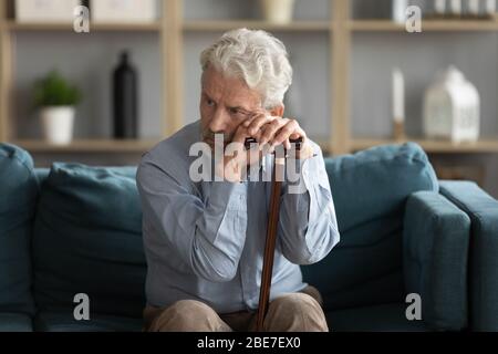 Müde aufgeregt reifen Mann, der Gehstock, auf der Couch sitzen Stockfoto