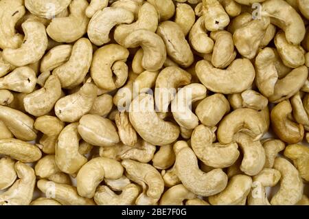 Cashewnüsse stapeln Nahaufnahme. Cashewnüsse Foto Hintergrund. Bio-Lebensmittel. Leckerer gesunder Snack. Verstreute Nüsse auf der Tischansicht. Cashewnüsse flach legen. Cas Stockfoto