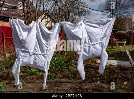 Zwei medizinische Mäntel trocknen auf einem Seil im Hof. Stockfoto