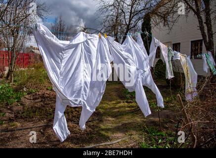 Zwei medizinische Mäntel trocknen auf einem Seil im Hof. Stockfoto