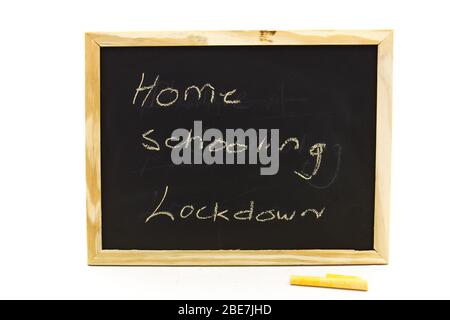 Kleine Tafel mit den Worten Home Schooling, die mit Kreide auf einem klaren Hintergrund in horizontalem Format isoliert darauf geschrieben sind Stockfoto