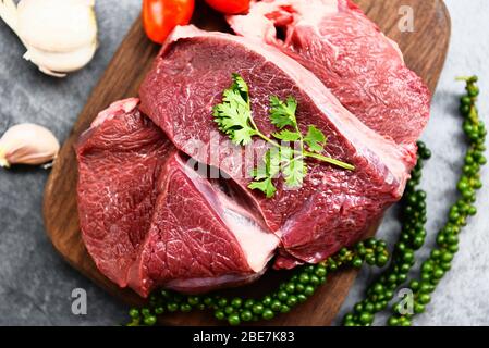 Rohes Rindfleisch auf Holzschneidebrett auf dem Küchentisch zum Kochen von Rindersteak geröstet oder gegrillt mit Zutaten Kraut und Gewürzen, frisches Rindfleisch ani Stockfoto