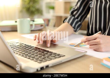 Nahaufnahme von Unternehmerhände Vergleich Graph Bericht auf Laptop auf dem Schreibtisch im Home Office Stockfoto