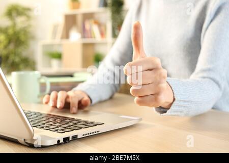 Nahaufnahme von Mädchen Hände Gesturing Daumen nach oben mit Laptop auf einem Schreibtisch zu Hause Stockfoto