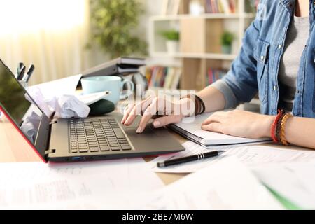 Nahaufnahme von chaotischen Studenten Mädchen Hände mit Laptop zu Hause auf einem unorganisierten Schreibtisch Stockfoto