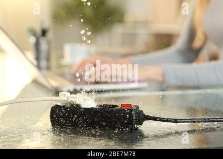 Nahaufnahme der Frau, die bei Gefahr von Stromschlag für Wasserlecks auf eine Steckdose Bank über einem Schreibtisch zu Hause fallen Stockfoto