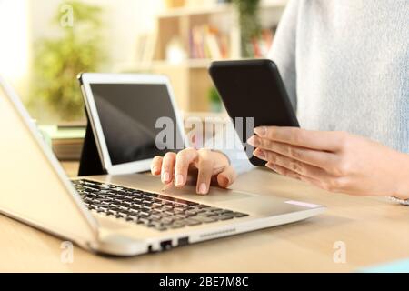 Nahaufnahme von Frauenhänden mit mehreren Geräten, die zu Hause auf einem Schreibtisch sitzen Stockfoto