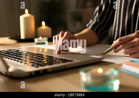 Nahaufnahme der Unternehmerin Hände arbeiten während eines Stromausfalls mit Kerzen sitzen auf einem Schreibtisch im Home Office in der Nacht Stockfoto