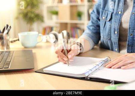 Nahaufnahme von Student Mädchen Hand Schreiben auf Notebook auf einem Schreibtisch zu Hause Stockfoto