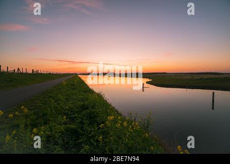 Farbenfrohe Landschaftsaufnahme des Himmels der Dämmerung über dem ruhigen Wasser eines kleinen Flusses Stockfoto