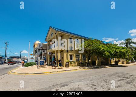 George Town, Grand Cayman Island, Großbritannien - 23. April 2019: Blick auf die Straße von George Town am Tag mit Fußgängern und Fischskulptur in der Nähe von Restaurant in Downto Stockfoto