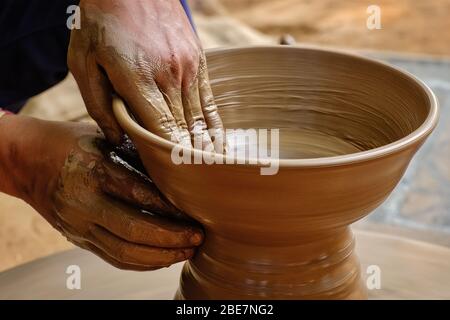 Töpferwaren - qualifizierte nasse Hände des Töpfers, die den Ton auf dem Töpferrad Formen Stockfoto