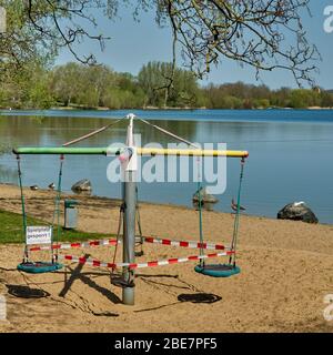 Geschlossenes Kinderkarussell am Ufer eines Freizeitsees, Schild mit deutscher Aufschrift: Spielplatz geschlossen Stockfoto