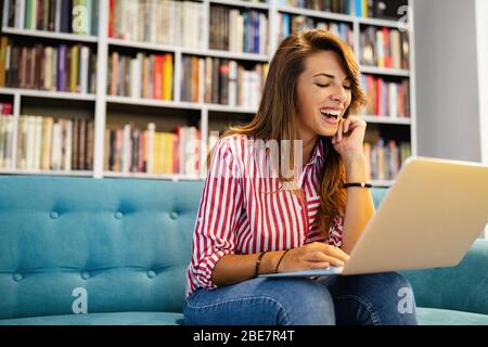 Glückliche junge Frau, die gute Nachrichten auf ihrem Notizbuch erhält Stockfoto