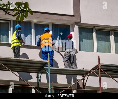Bukarest/Rumänien - 04.09.2020: Bauarbeiter auf einem Gerüst renovieren ein Mehrfamilienhaus Stockfoto