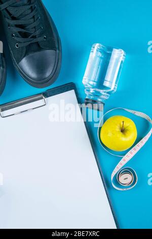 Diät-Plan. Weißes Blatt auf der Tablette und Äpfel mit Maßband auf hellblauem Hintergrund. Schlankheits- und Entgiftungskonzept Stockfoto