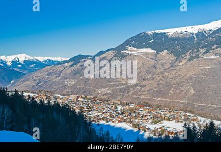 Panoramablick über Verschneiten alpinen Gebirge Alpen auf blauen Himmel Hintergrund mit Mountain Village Stockfoto