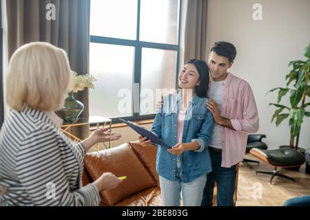 Junges Paar. Dunkelhaariger großer Mann und seine Freundin sprechen mit der Psychologin in ihrem Schrank Stockfoto