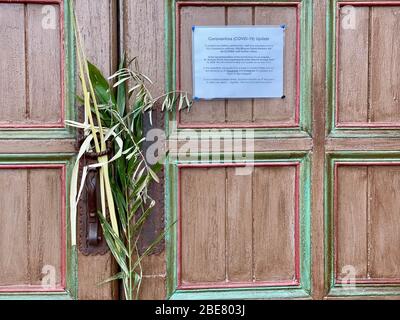 Santa Barbara, Kalifornien, USA. April 2020. Am Ostersonntag werden Blumen an der Tür der Historischen Mission in Santa Barbara zurückgelassen, die ihre Kirche während des Ausbruchs von Covid-19 geschlossen hat. Das Schild an der Tür lädt die Gemeindemitglieder ein, die Dienste online zu sehen. Quelle: Amy Katz/ZUMA Wire/Alamy Live News Stockfoto