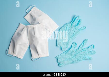 Schutzmasken und Einweg-Latexhandschuhe auf einer farbigen Oberfläche Stockfoto
