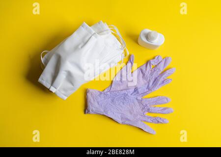 Schutzmasken, Desinfektionsmittel und Einweg-Latexhandschuhe auf einer farbigen Oberfläche Stockfoto