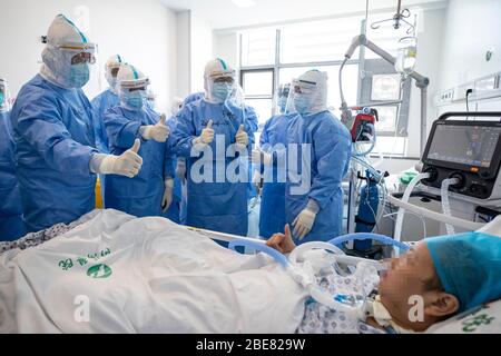 (200413) -- WUHAN, 13. April 2020 (Xinhua) -- Medizinische Mitarbeiter feuern einen Patienten auf, der auf die Intensivstation (ICU) einer Station verlegt werden soll, nachdem alle Patienten aus dem Zhongfaxincheng Campus des Tongji Krankenhauses, das der Huazhong Universität für Wissenschaft und Technologie in Wuhan, der zentralen Provinz Hubei, angeschlossen ist, verlegt wurden. 12. April 2020. Die Stationen im 9. Stock von Gebäude C auf dem Zhongfaxincheng Campus des Tongji Krankenhauses, das der Huazhong Universität für Wissenschaft und Technologie angeschlossen ist, die von medizinischen Teams vom Peking Union Medical College Hospital übernommen wurde Stockfoto