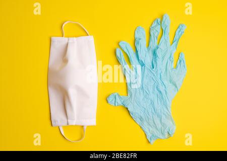 Schutzmasken und Einweg-Latexhandschuhe auf einer farbigen Oberfläche Stockfoto