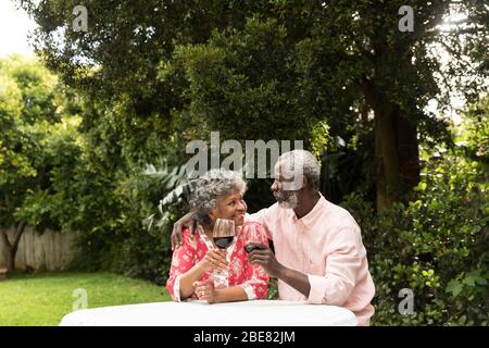 Ein afroamerikanisches Paar, das im Garten sitzt und trinkt Stockfoto