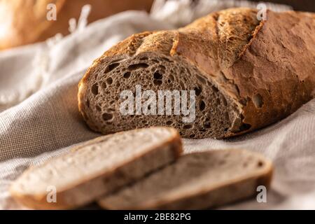 Zwei Scheiben frisch gebackenes Brot auf den Laib und ein Leinentuch mit einem Messer auf der Seite. Stockfoto
