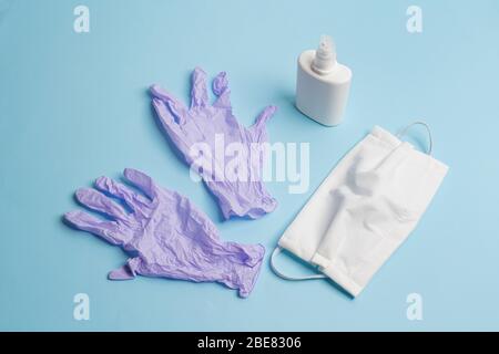 Schutzmasken, Desinfektionsmittel und Einweg-Latexhandschuhe auf einer farbigen Oberfläche Stockfoto