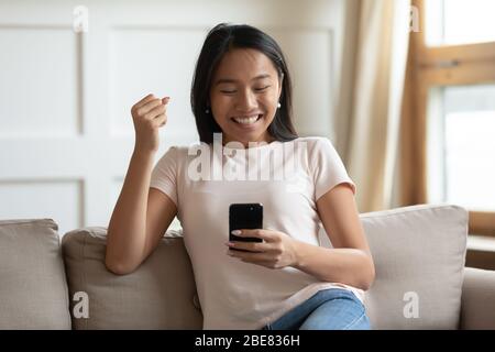 Aufgeregt asiatische Frau halten Smartphone Nachricht lesen fühlt sich glücklich Stockfoto