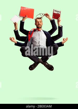 Junger kaukasischer Geschäftsmann, Manager, der alles verwaltet, viele Dinge. Termin, Zeitmanagement. Moderne Shiva, ruhig und ausgeglichen. Büroarbeit, tägliche Aufgabe. Papier, Kaffee, Mappen, Bleistifte. Stockfoto