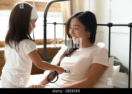 Asiatisch kleines Mädchen halten Phonendoskop hört Herzschlag zu Mutter Stockfoto