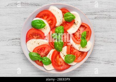 Köstlicher Caprese-Salat mit reifen Tomaten und Mozzarella-Käse mit frischen Basilikumblättern. Italienische Küche. Aussicht von oben Stockfoto