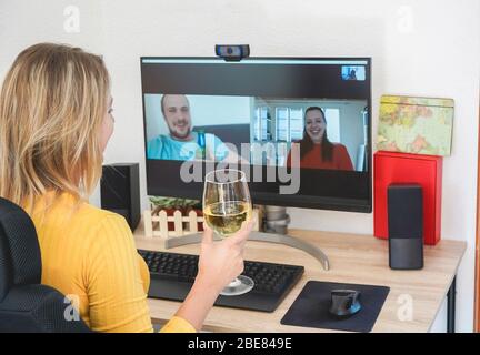 Junge Frau im Gespräch mit Freunden Wein trinken und zusammen lachen - Alternative Party während der häuslichen Isolation Quarantäne - Fokus auf Glas Hand Stockfoto